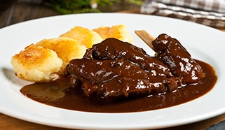 Dušené zaječí stehno s černou omáčkou a opečenými škubánky