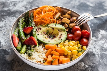 Lunch Bowl mit Bulgur, grünem Spargel, Erdbeeren, Karotten, Tofu, Tomaten, Mais, Süßkartoffeln und Avocado