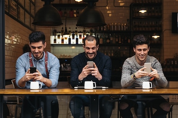 Drei Männer sitzen in einem Café und erhalten die korrekte Sprachversion der Restaurant-Website.
