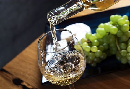 Verre de vin blanc, planche de fromages et grappe de raisin