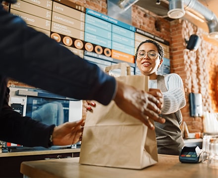 Serveuse donnant une commande à emporter à un livreur