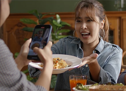 Une cliente prend en photo le plat de sa voisine