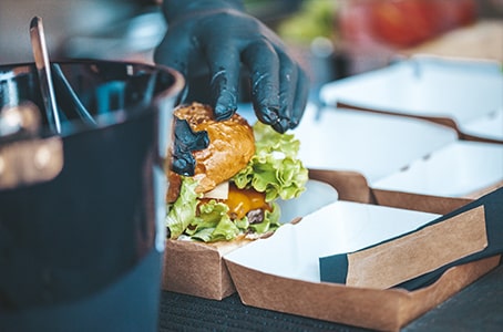 Mise d’un burger dans une boîte en carton pour la vente à emporter