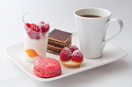 Café gourmand et gâteaux sur assiette blanche