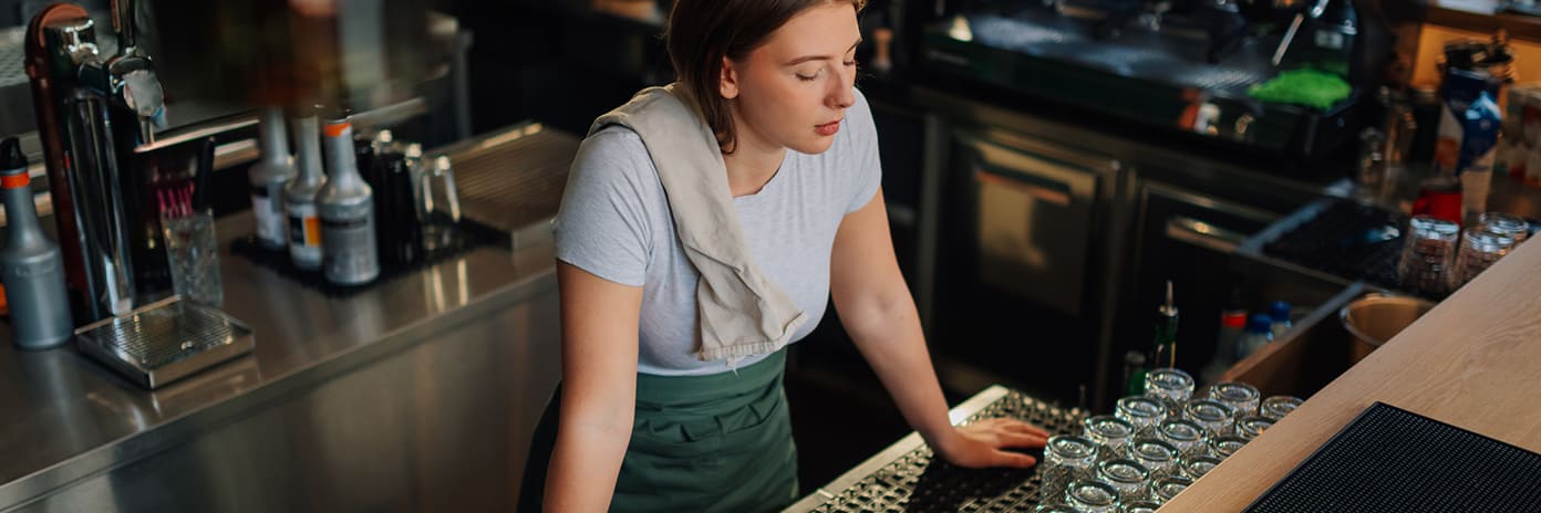 Jeune barmaid fatiguée appuyée sur le comptoir du bar dans un café