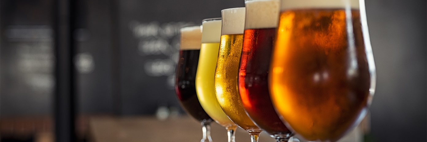5 verres de bière de 5 couleurs différentes sur un comptoir