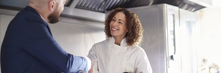 Poignée de mains entre une restauratrice et un homme en costume
