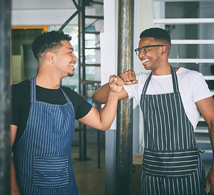 Deux serveurs de restaurants se souriants en faisant un check