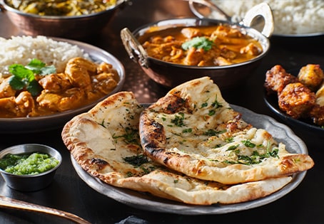 Cheese naan accompagnés de poulets et de riz dans différents plats sur une table de restaurant