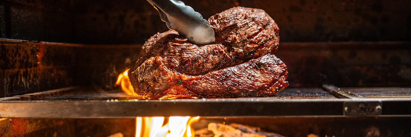 Steak grillé sur feu ouvert avec du bois brûlant et des flammes