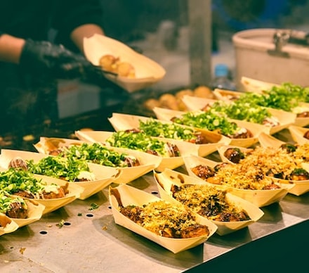 Préparation de plats à emporter, disposés sur le plan de travail d'une dark kitchen