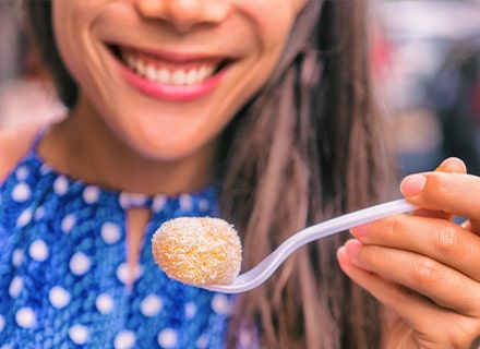 Femme souriante avec un mochi dans une cuillère