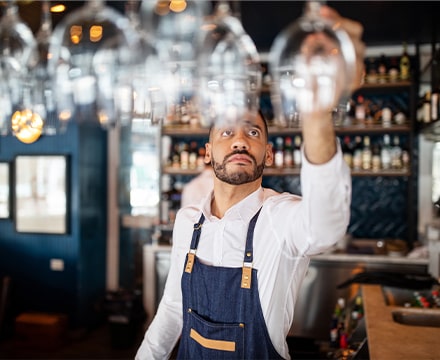 Serveur rangeant des verres au dessus du comptoir d'un restaurant
