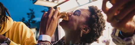 Jeune femme qui mange une pizza avec ses amis