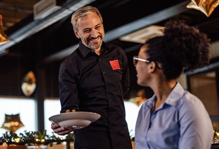 Serveur souriant apportant un plat