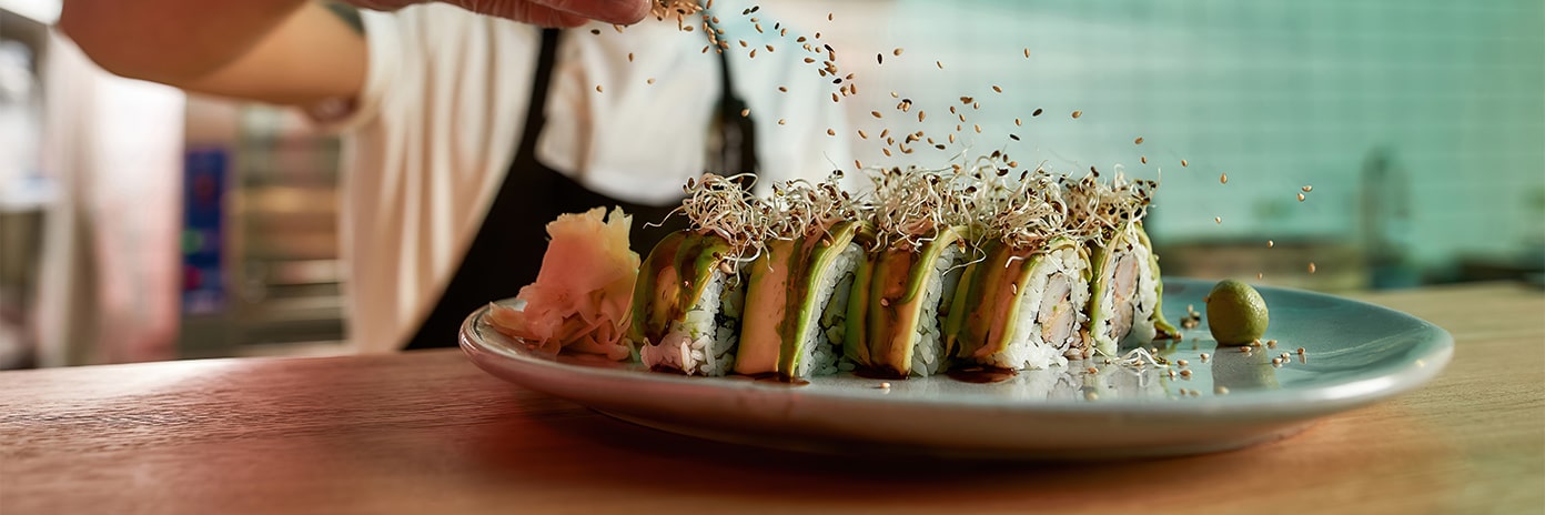 Chef recouvrant des sushis avec des graines germées