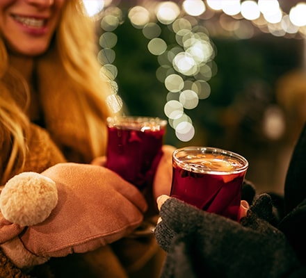Mugs de vin chaud tenus avec des moufles