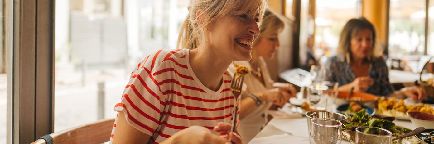 Une cliente souriante mange son plat au restaurant