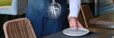 Placement d'une assiette et des verres par un serveur sur une table de restaurant Placement d'une assiette et des verres par un serveur sur une table de restaurant