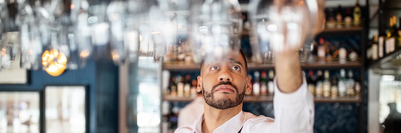 Serveur qui s’empare d’un verre de vin au bar