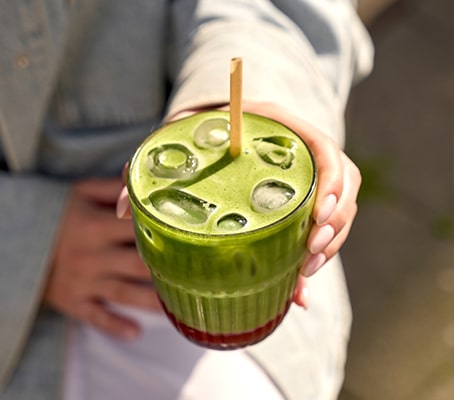 Femme tenant un matcha latte glace avec une paille
