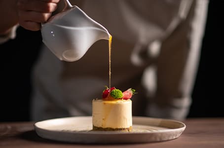 Un chef verse de la sauce sur un gâteau aux fruits