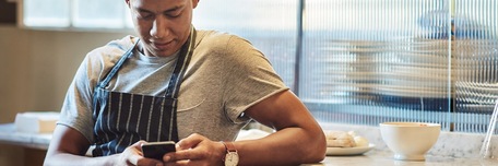 Un gérant de restaurant communique sur les réseaux sociaux via son smartphone