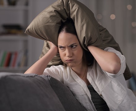 Femme qui se protège du bruit avec un cousin