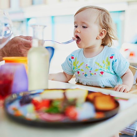 Jeune enfant sur une chaise bébé au restaurant