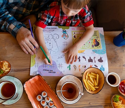 Enfant occupé par un coloriage à la table d'un restaurant
