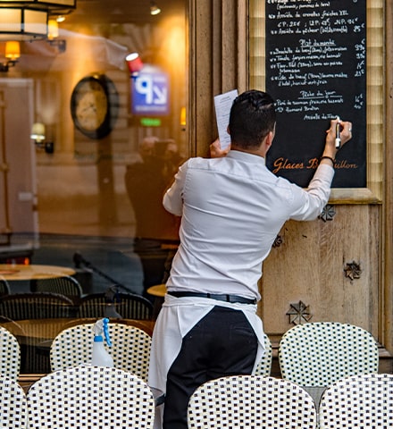 Serveur écrivant le menu sur l'ardoise d'un restaurant