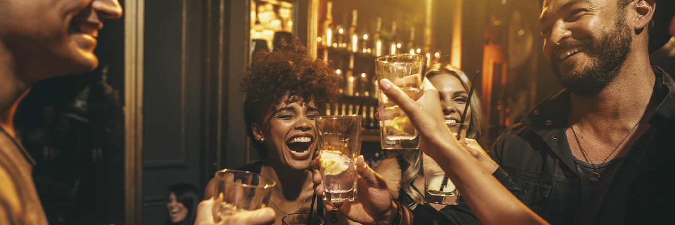 Groupe d'amis souriants dans un bar avec des verres à la main