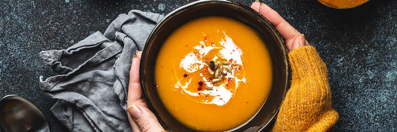 Bol de soupe de potiron entre les mains d'une femme