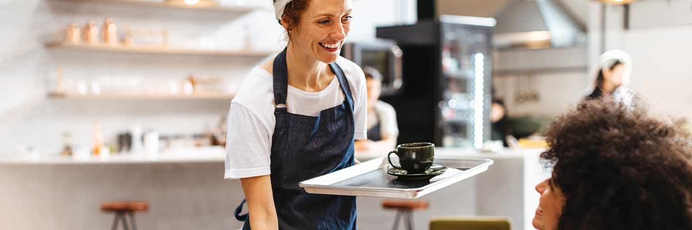 Serveuse qui sert une boisson chaude et une part de gâteau à une cliente