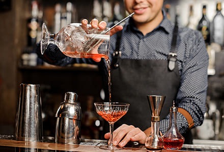 Barman ajoutant un alcool rouge dans le verre à cocktail