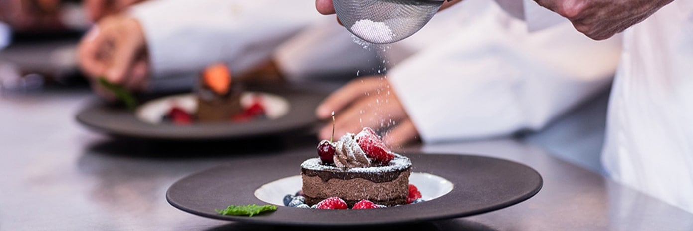 Gros plan de chef réalisant la finition d'un dessert