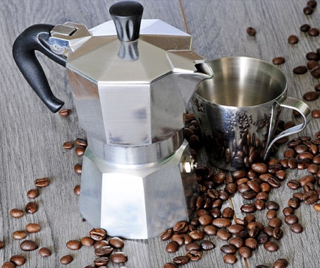 Cafetière italienne et grains de café sur une table