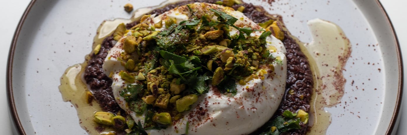 Burrata, olives et sumac accompagné de pistache dans une assiette