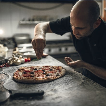 Un chef compose la garniture de sa pizza