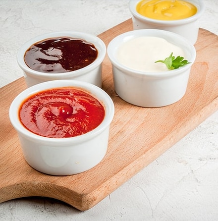 Plusieurs sauces de couleur différente sur un plateau en bois