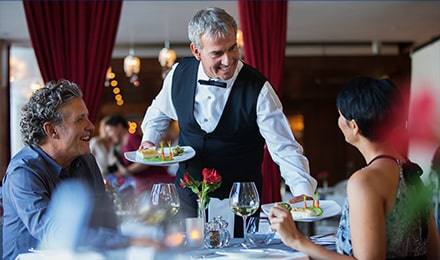 Serveur souriant apportant les plats à la table de clients