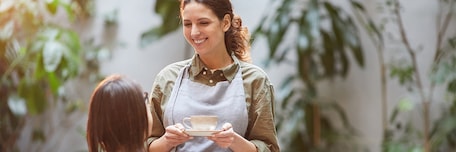 Serveuse souriante apportant un café à la table d'une cliente