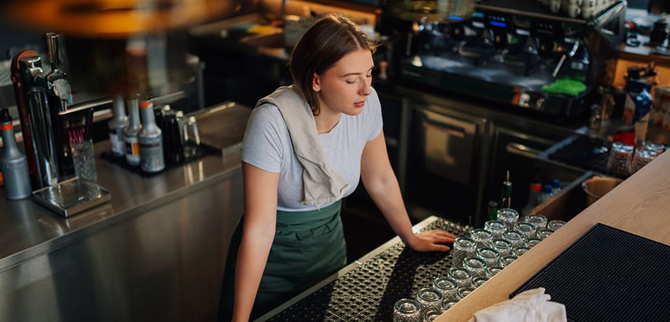 Jeune barmaid fatiguée appuyée sur le comptoir du bar dans un café