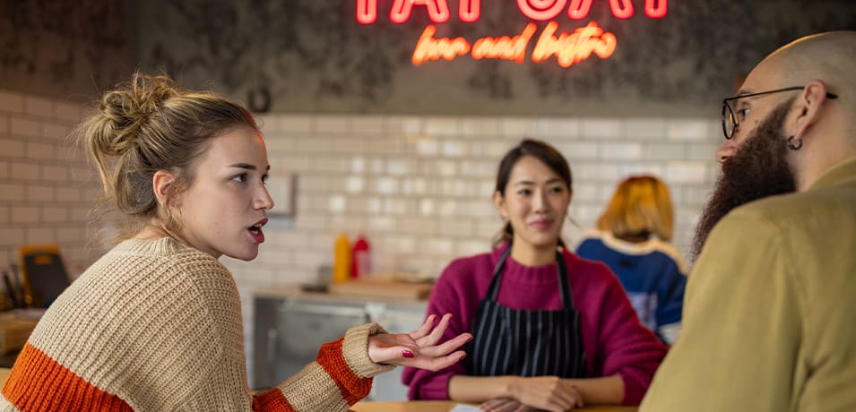 Jeune couple qui se décide sur leur commande face à la serveuse