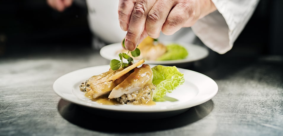 Chef cuisinier réalisant le dressage d'une assiette avec du poulet