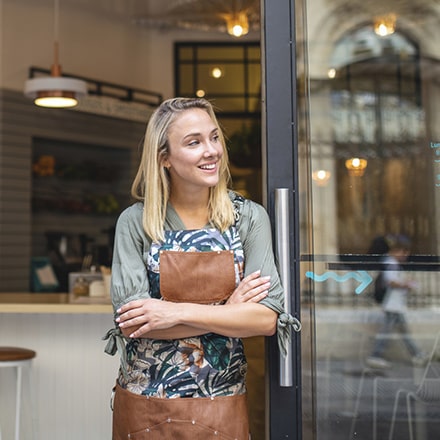 Femme devant la porte de son restaurant