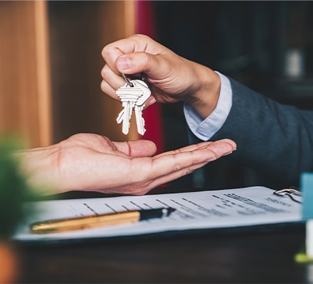 Main d'un homme tenant des clés au dessus de la main d'une autre personne