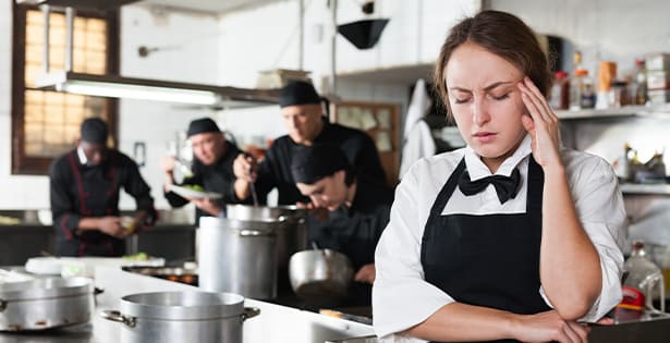 Serveuse dans une cuisine de restaurant qui se tient la tête