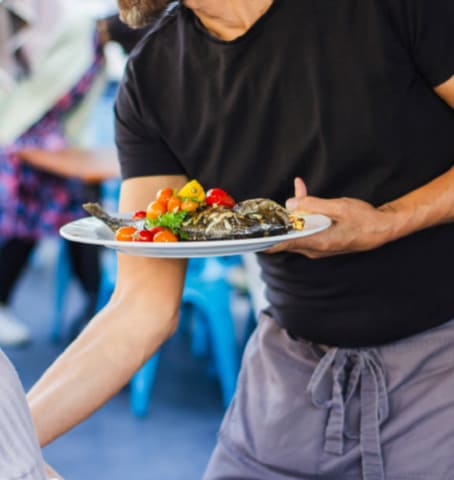 Serveur qui apporte une assiette de poisson dans un restaurant