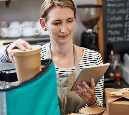 Femme préparant une commande de restaurant en regardant sur une tablette